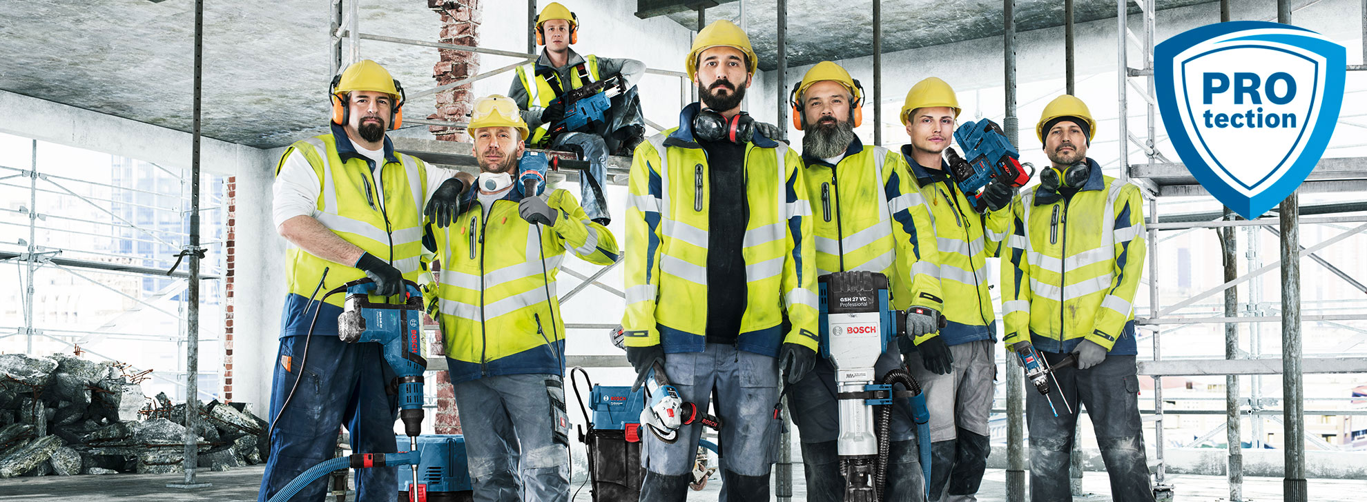 Seven workers in safety vests and helmets hold Bosch tools on a construction site.