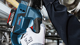 A Bosch Professional tool held by a gloved hand, set in a workshop environment.
